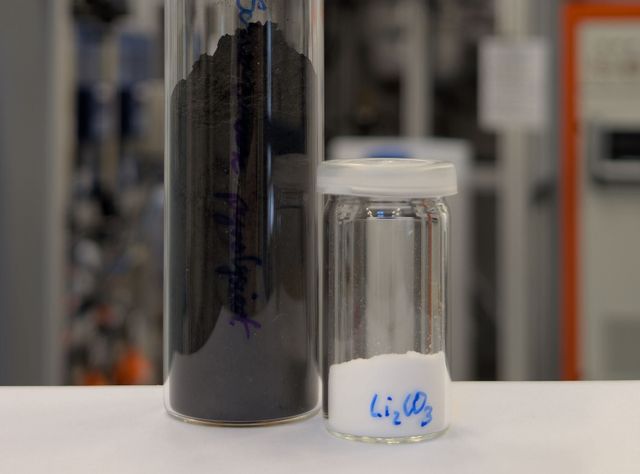 Schwarzmasse aus Lithium-Ionen-Batterien und daraus extrahiertes Lithiumcarbonat Zwei Glasgefäße: Eines enthält Schwarzmasse und das zweite weißes Lithiumcarbonat
