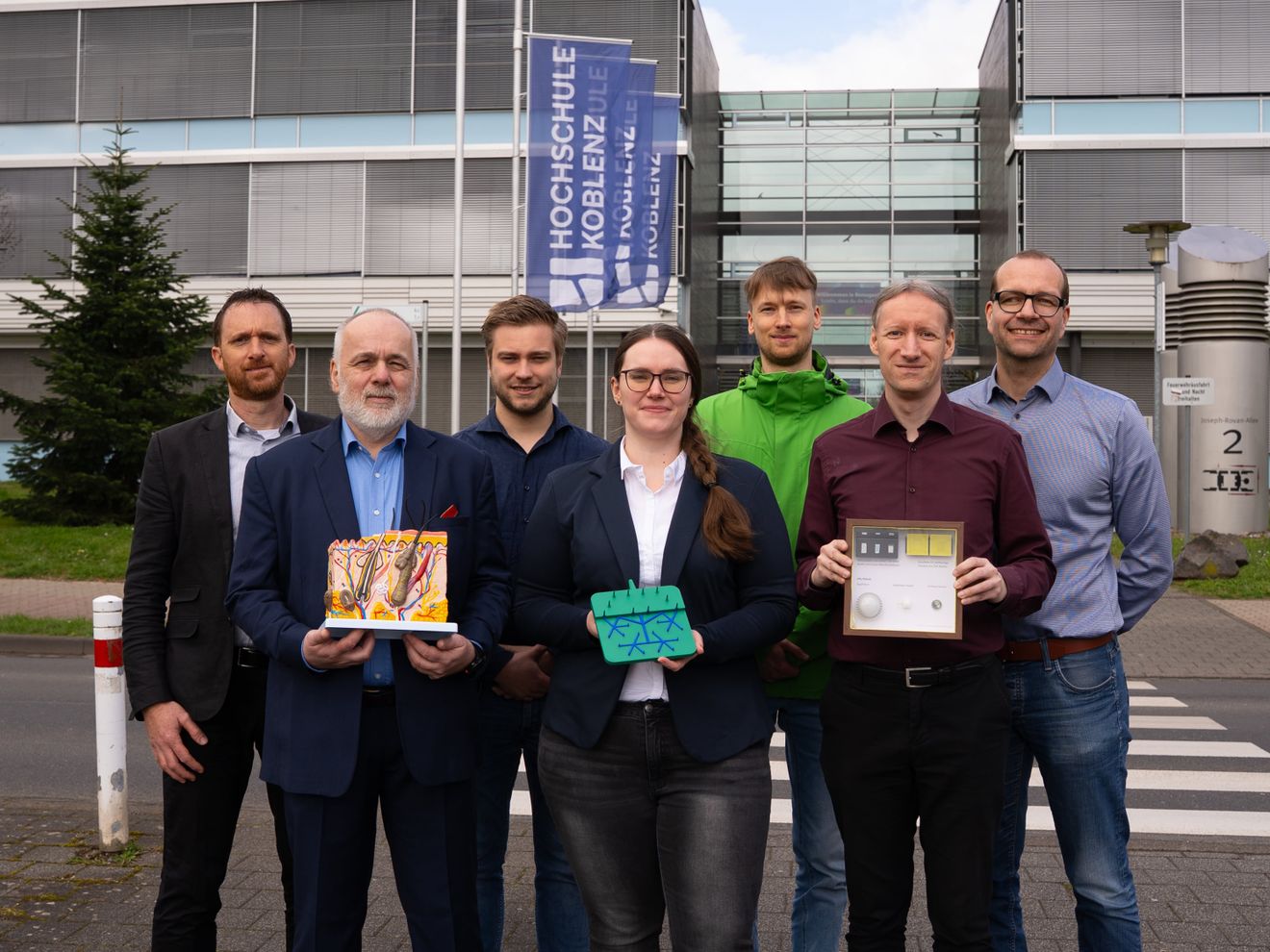 Biomarker minimalinvasiv messen: Hochschule Koblenz entwickelt Mini-Labor für die Haut Die Beteiligten der Forschungsgruppe zeigen modellhaft einen Querschnitt durch die Haut, ein vergrößertes Mikronadelpatch sowie Modelle der Patches in Originalgröße.