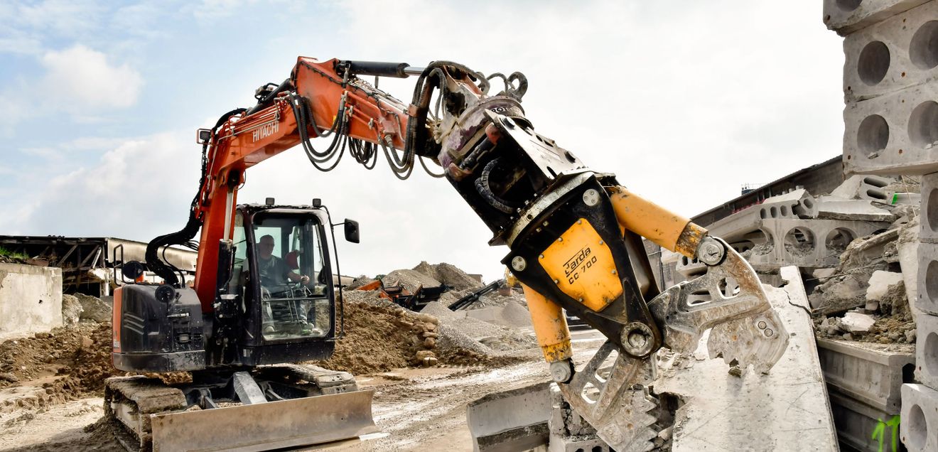 Ein Hitachi Zaxis ZX85US-6 im typischen Orange bricht mit seiner Zange eine Mauer ab