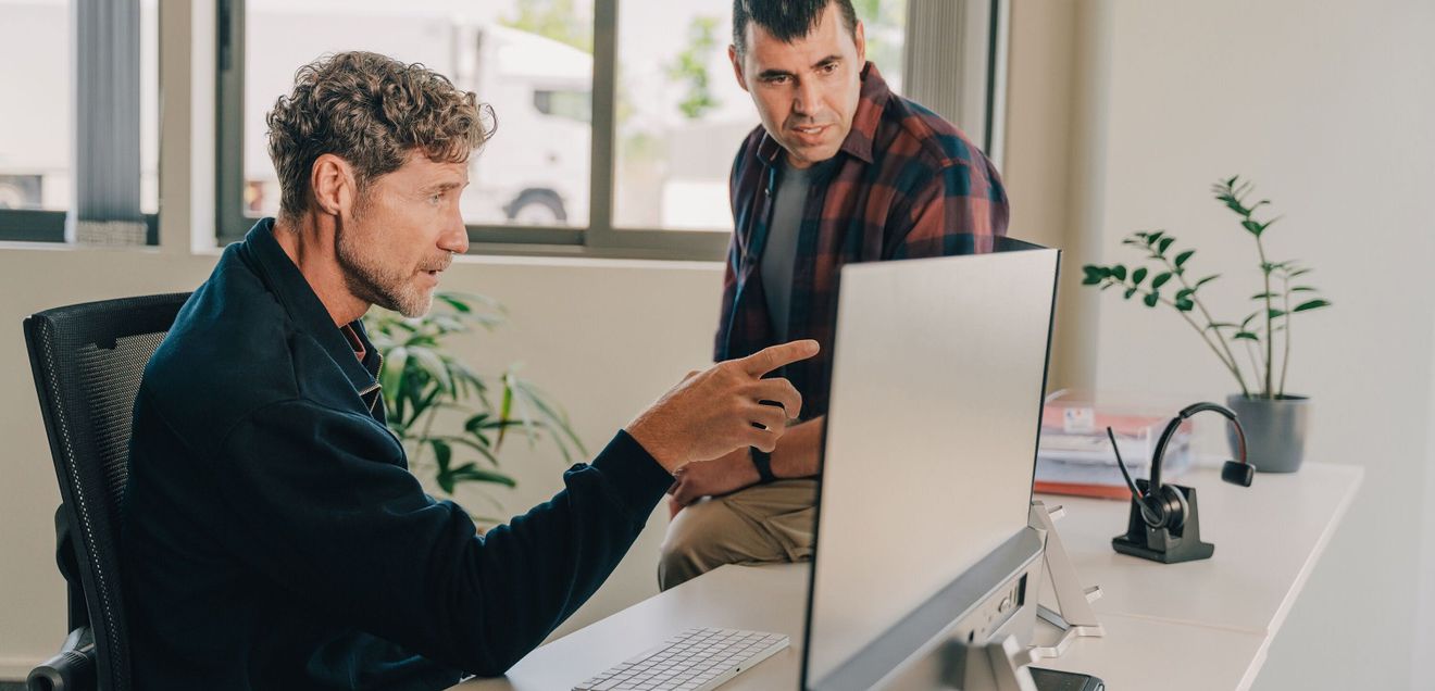 Compliance mit Webfleet Zwei männliche Mitarbeitende managen die Telematik und das Fuhrparkmanagement mit Webfleet