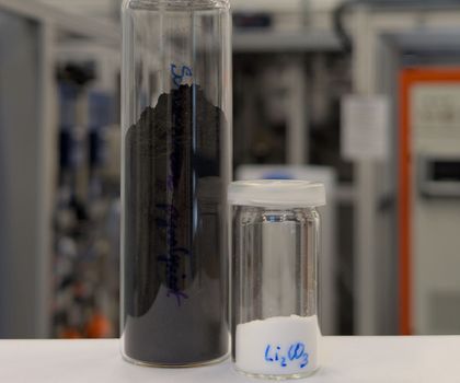 Zwei Glasgefäße: Eines enthält Schwarzmasse und das zweite weißes Lithiumcarbonat