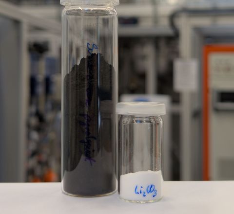 Zwei Glasgefäße: Eines enthält Schwarzmasse und das zweite weißes Lithiumcarbonat