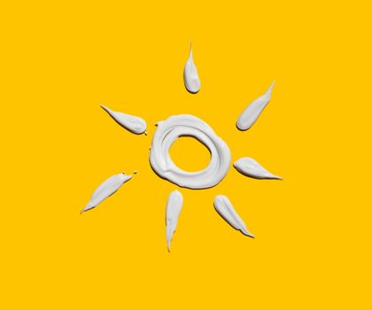Symbolbild Sonne aus Sonnencreme auf gelbem Hintergrund