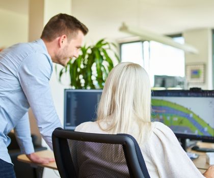 Ein männlicher und ein weiblicher Mitarbeiter prüfen die Logistik auf einem Computerbildschirm