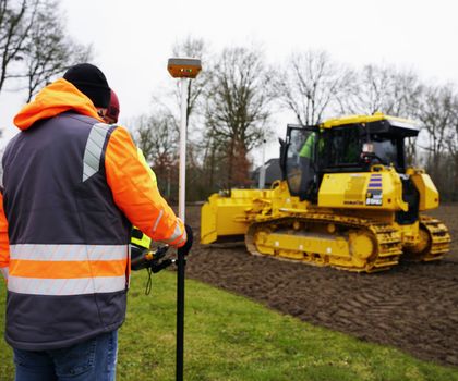 Dozer Ein gelber Komatsu-Dozer mit GNSS-Steuerung schafft ein Planum auf einer Wiese
