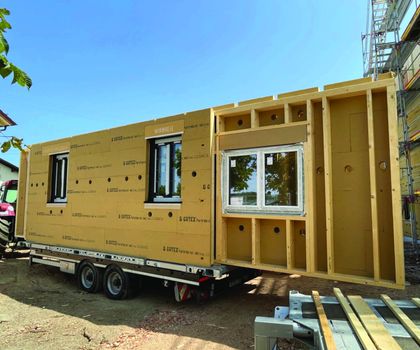 Module Holzmodulwände werden auf einem Tieflader zur Baustelle transportiert.