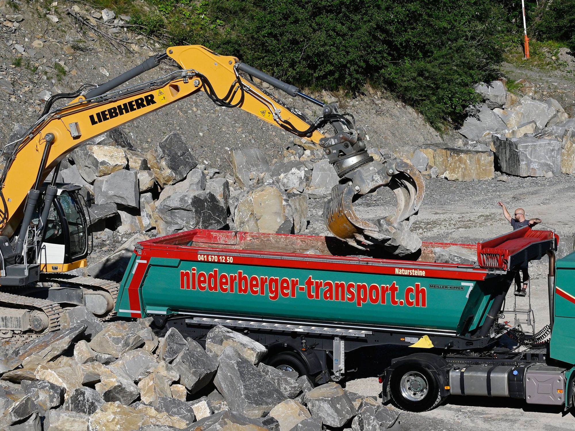 Ein Meiller Grandload Kippsattelanhänger wird mit Steinen beladen