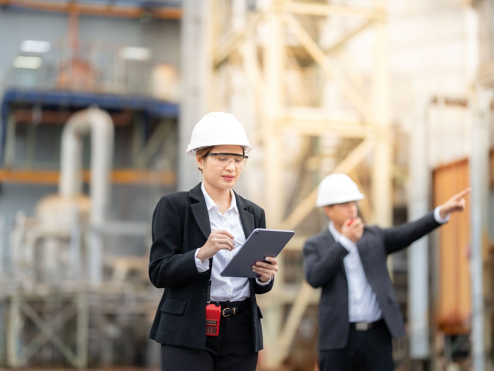 Qualitätsmanagement Eine Frau mit Tablet, Schutzbrille Helm bei einem Rundgang durch eine Werksanlage