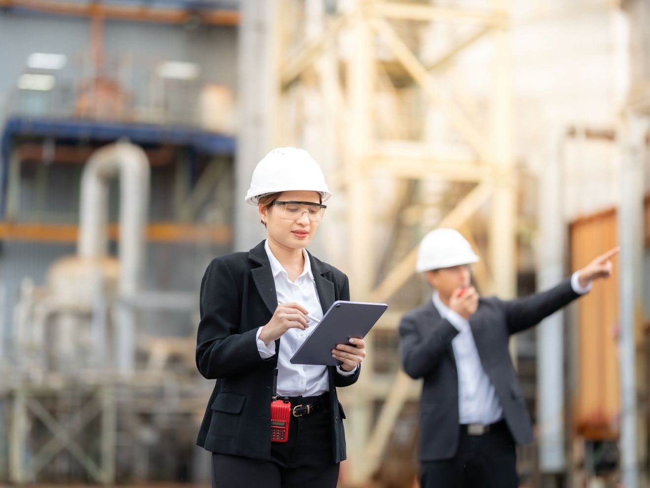 Qualitätsmanagement Eine Frau mit Tablet, Schutzbrille Helm bei einem Rundgang durch eine Werksanlage