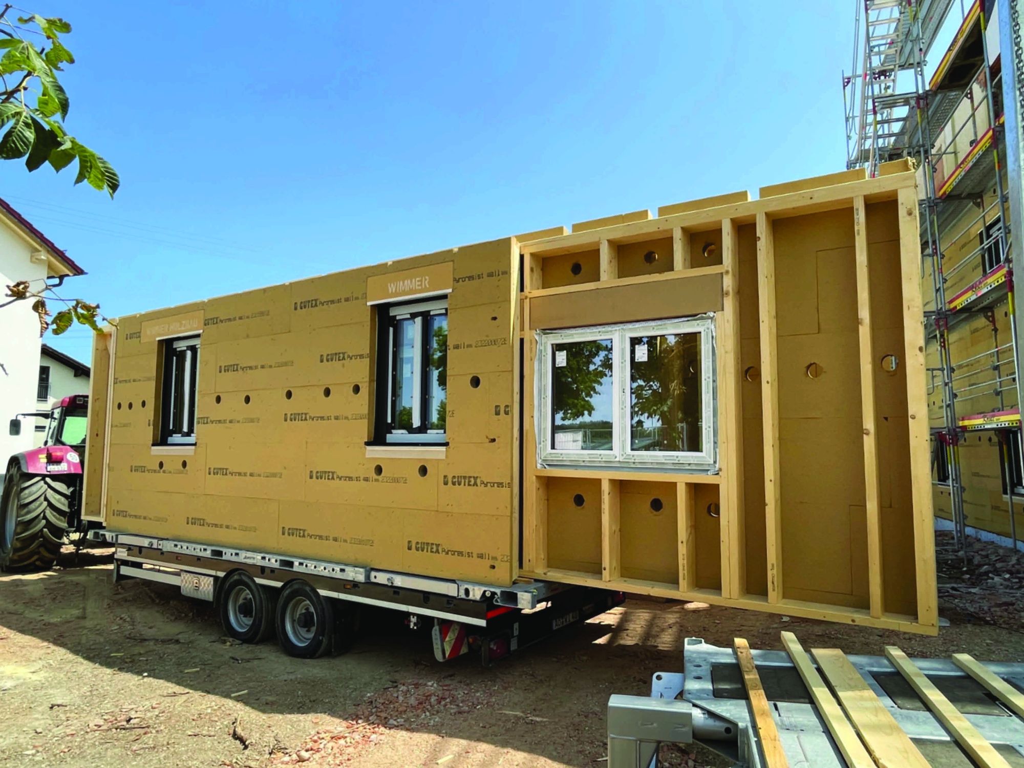 Module Holzmodulwände werden auf einem Tieflader zur Baustelle transportiert.