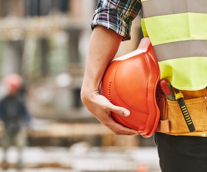 Baustelle Ein Bauarbeiter mit Helm an der Hüfte auf einer Baustelle