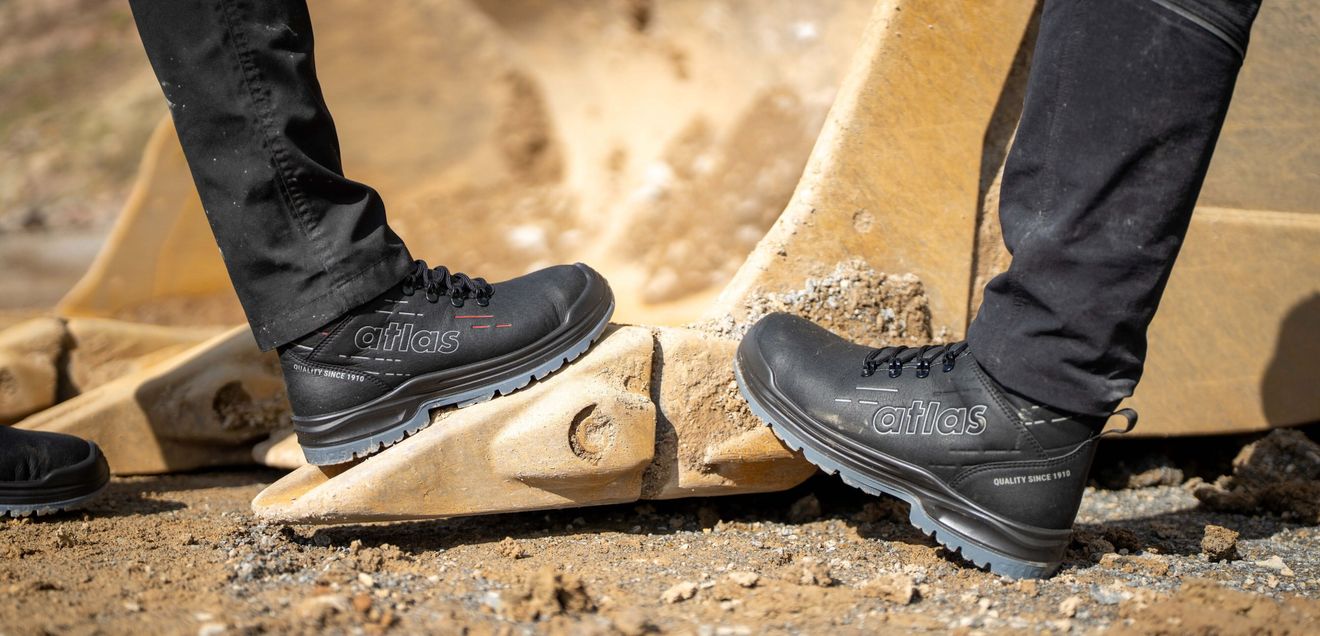 Atlas Schuhe Zwei Paar Atlas-Schuhe auf einer Baustelle in einer Baggerschaufel