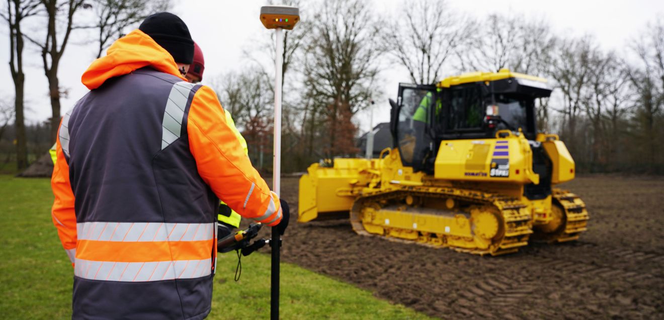 Dozer Ein gelber Komatsu-Dozer mit GNSS-Steuerung schafft ein Planum auf einer Wiese