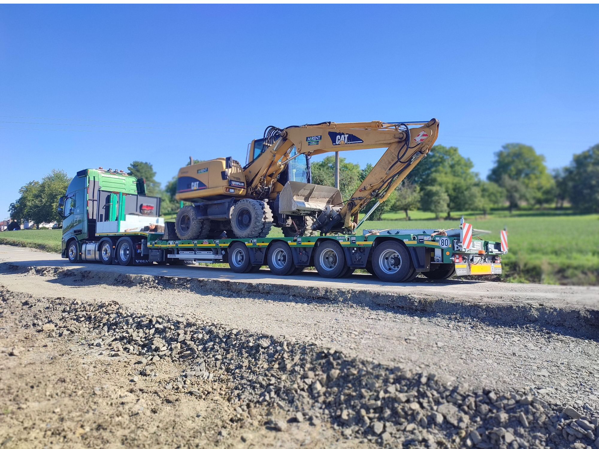 ein Goldhofer Anhänger, auf dem ein Caterpillar-Bagger steht, samt Zugmaschine