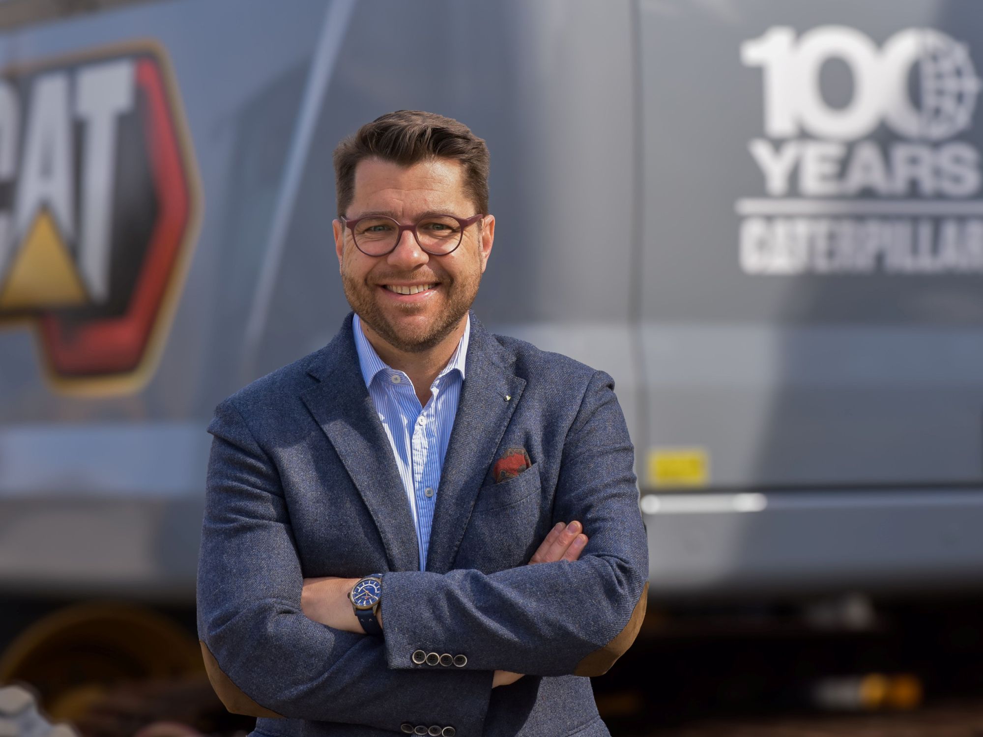 Henning Jansen lächelt vor einem Caterpillar Bagger in die Kamera