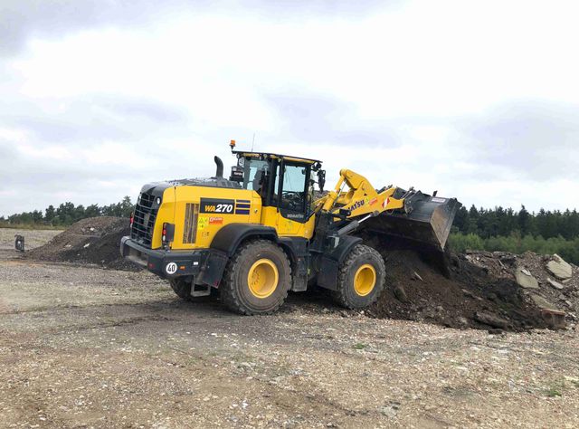 Ein Komatsu WA270-8 entlädt Erde aus seiner Schaufel