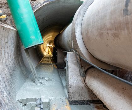 Ein grüner Schlauch ragt in den Leitungstunnel und gießt Füllmaterial um diesen zu verschließen