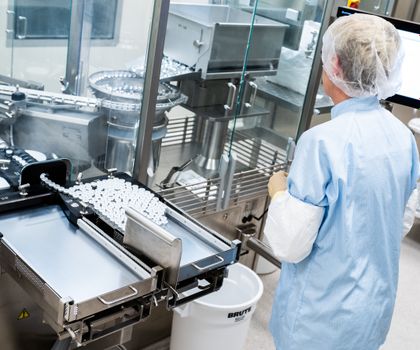 Mitarbeiterin im Labor Eine Arbeiterin steht an einer Abfüll- und Verschließanlage für pharmazeutische Produkte bei Takeda Pharmaceutical.