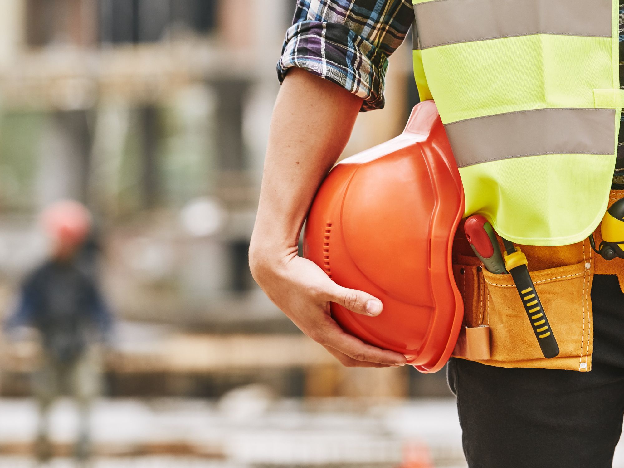 Ein Bauarbeiter mit Helm an der Hüfte auf einer Baustelle