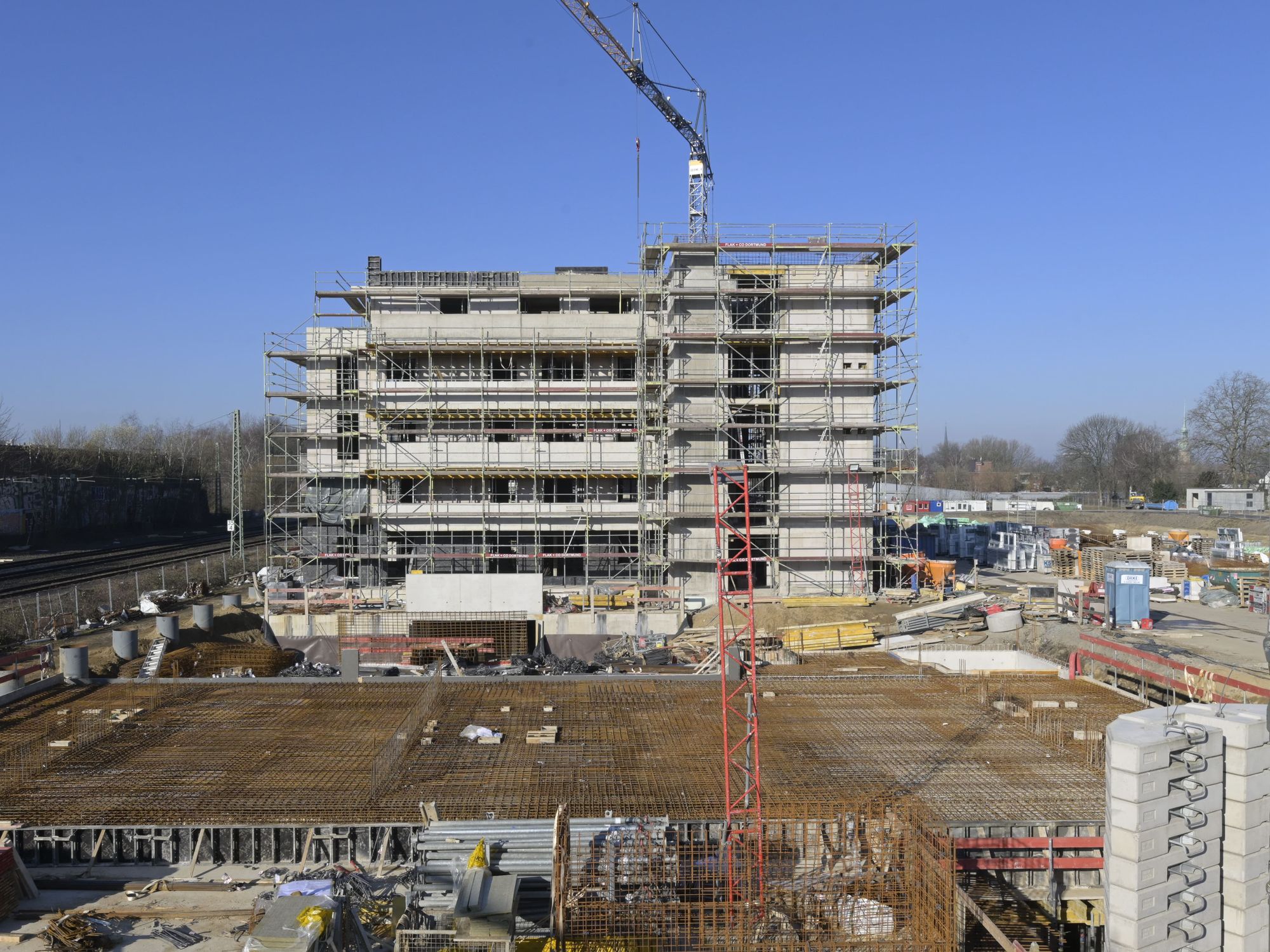 Baustelle eines Mehrparteienhauses, auf der Baumaschinen und Geräte stehen
