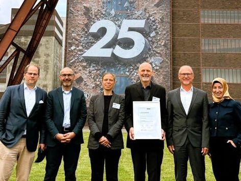 Präsidium und Geschäftsführung des VUP mit neuem Ehrenpräsidenten Sechs Personen (Präsidium und Geschäftsführung des VUP) stehen vor dem Förderturm der Zeche Zollverein in Essen