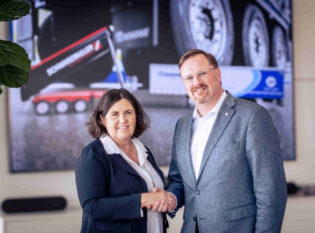 Beate Paletar, Eigentümerin der Schwarzmüller Gruppe und Bernard Krone, Aufsichtsratsvorsitzender der Krone Gruppe schütteln  sich die Hände und lächeln in die Kamera