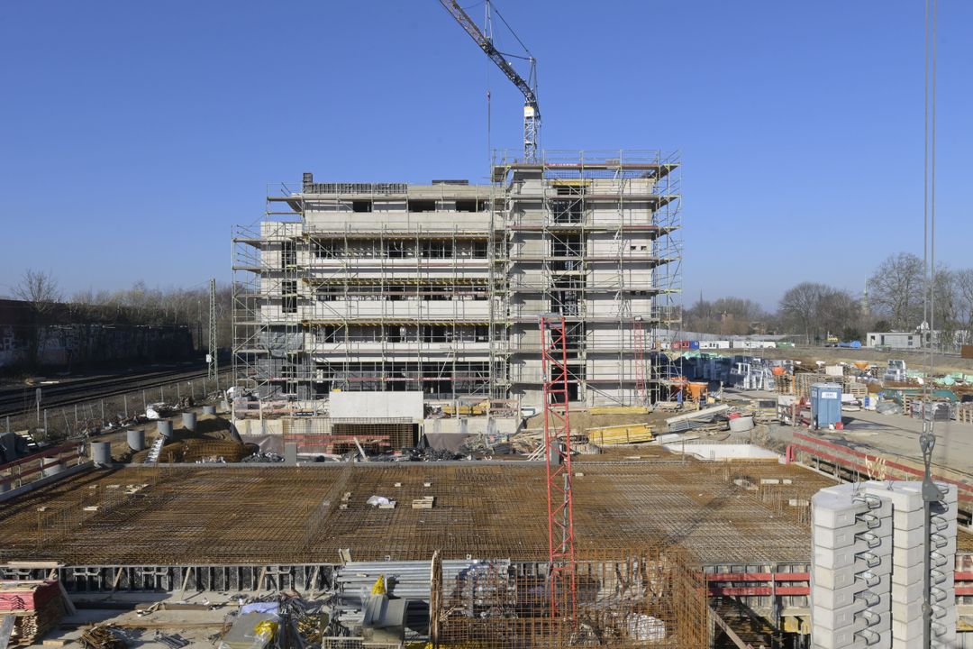 Baustelle eines Mehrparteienhauses, auf der Baumaschinen und Geräte stehen