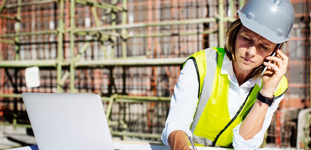 Arbeiterin Einw Arbeiterin mit Smartphone und Laptop auf der Baustelle