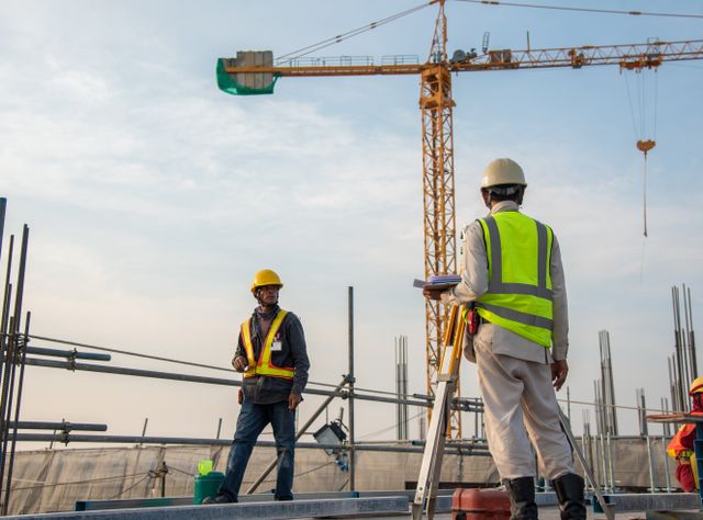Bauarbeiter auf einer Baustelle vor Kranen