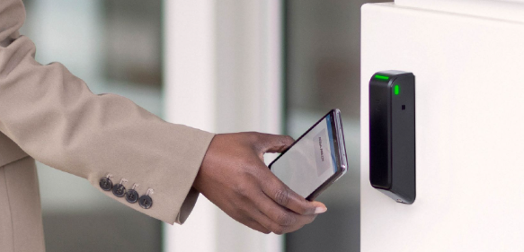 Zutrittslösung für komplexe Gebäudeöffnungen: Kartenleser von Assa Abloy mit integrierten Relais Mitarbeiterin nutzt Kartenleser von Assa Abloy zur Öffnung einer Unternehmenstür