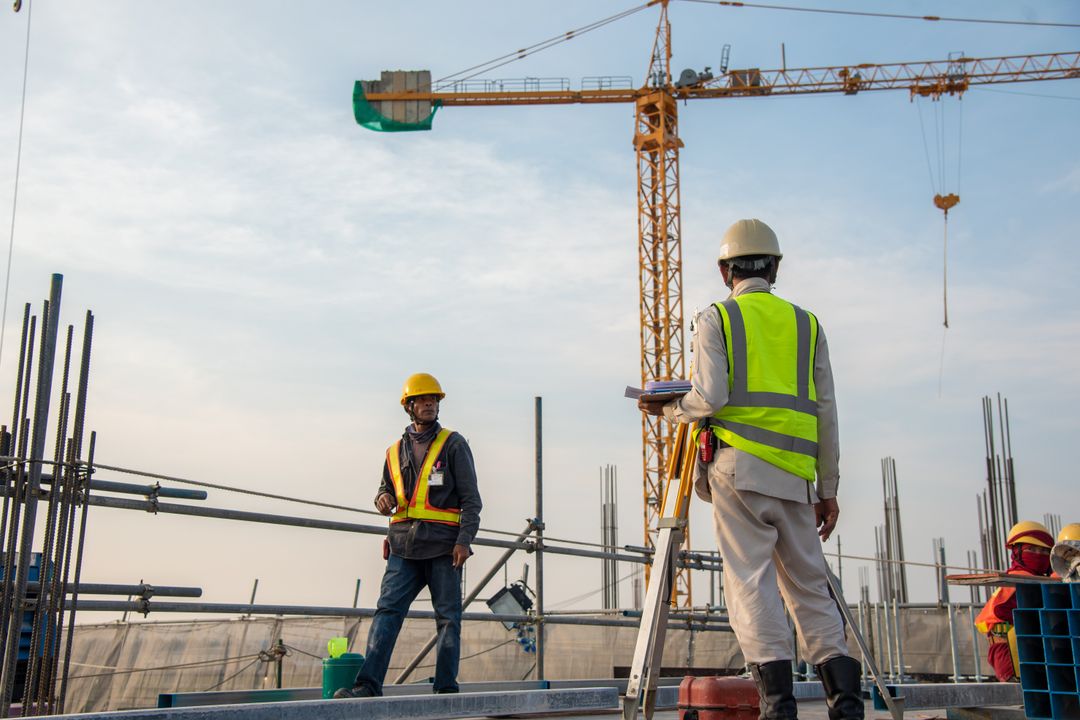 Bauarbeiter auf einer Baustelle vor Kranen