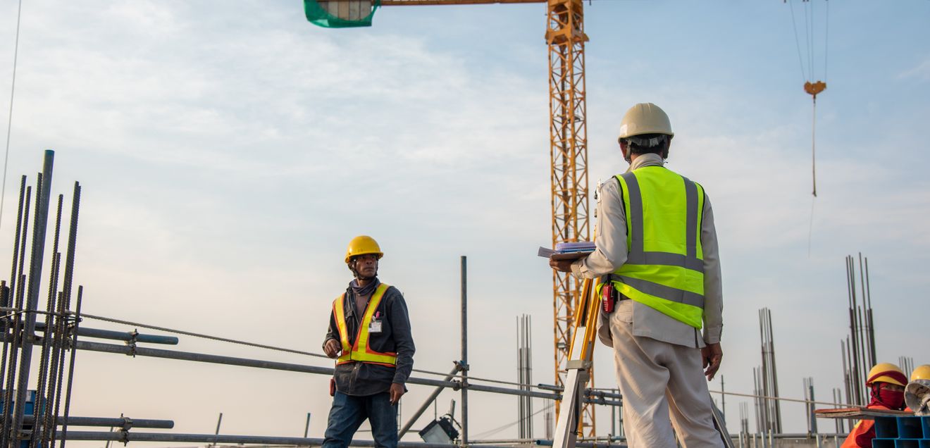 Bauarbeiter auf einer Baustelle vor Kranen