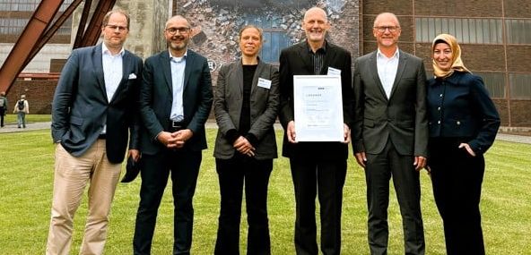 Präsidium und Geschäftsführung des VUP mit neuem Ehrenpräsidenten Sechs Personen (Präsidium und Geschäftsführung des VUP) stehen vor dem Förderturm der Zeche Zollverein in Essen