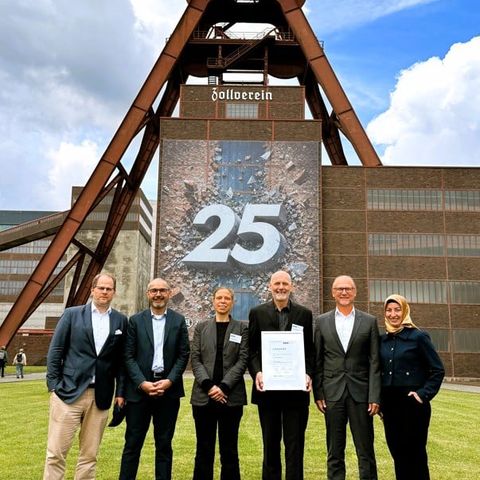 Sechs Personen (Präsidium und Geschäftsführung des VUP) stehen vor dem Förderturm der Zeche Zollverein in Essen