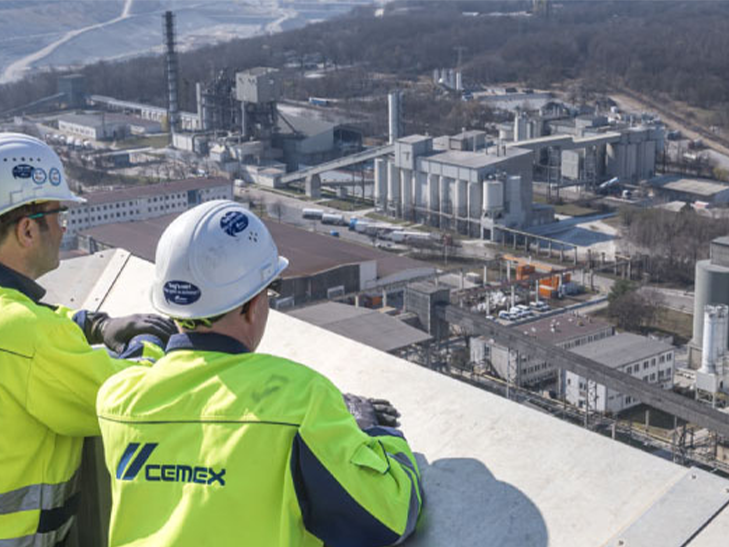 Zwei Arbeiter blicken auf eine Anlage von Cemex zur Baustoffherstellung