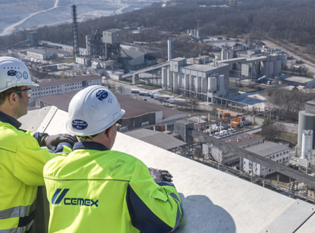 Zwei Arbeiter blicken auf eine Anlage von Cemex zur Baustoffherstellung