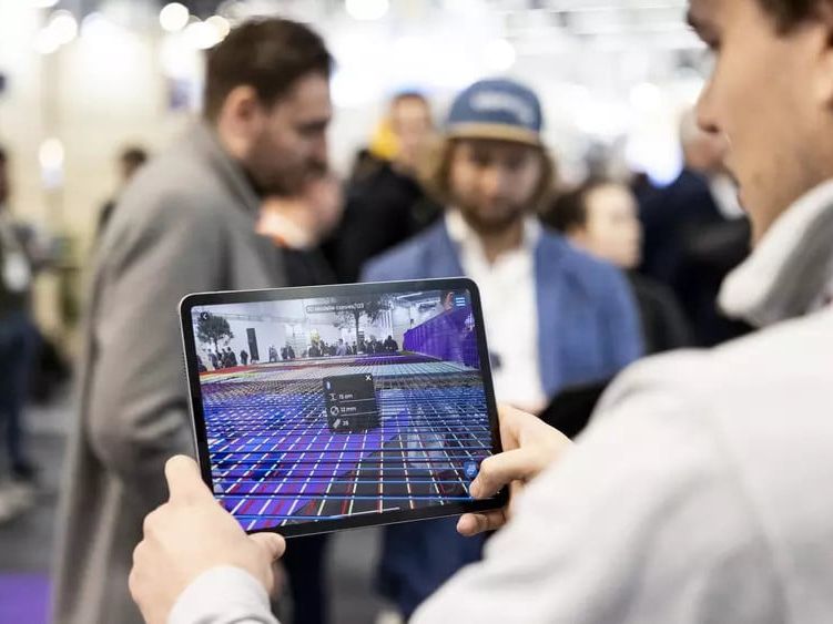 Ein Mann hält ein Tablet in der Hand, das ein 3D-Modell der Umgebung anlegt