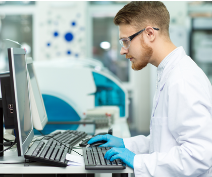 Forscher mit Labor Schutzbrille am PC Forscher mit Labor Schutzbrille am PC