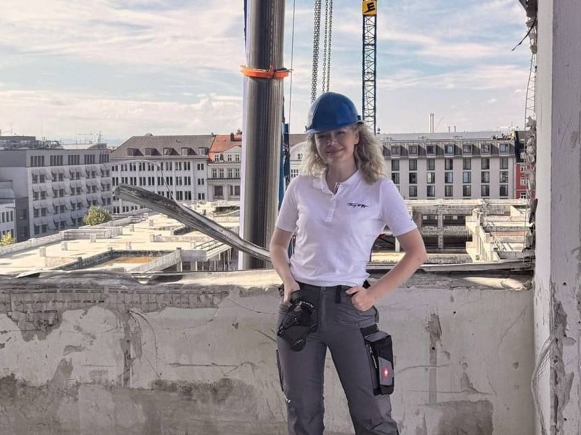 Daria Stützer lächelt von einer Baustelle in der Kamera