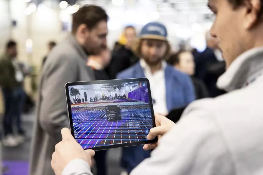 Ein Mann hält ein Tablet in der Hand, das ein 3D-Modell der Umgebung anlegt