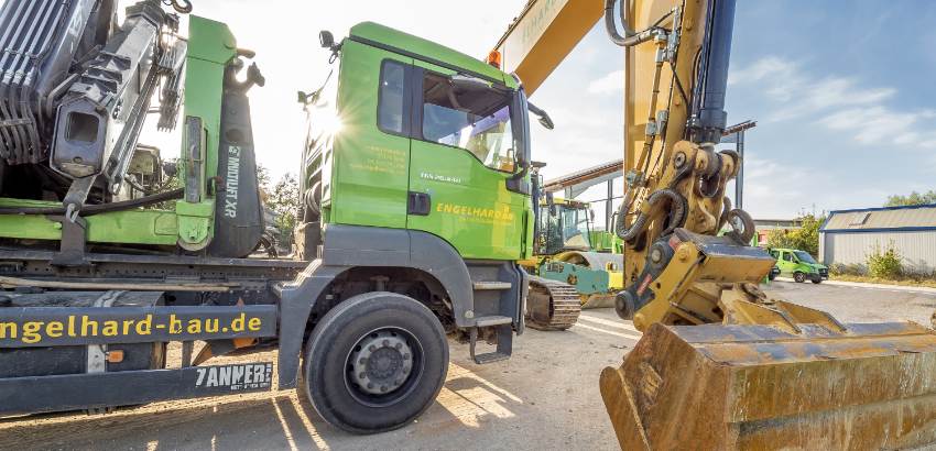 Ein Lastwagen und ein Ausleger eines Baggers auf einer Baustelle Ein Lastwagen und ein Ausleger eines Baggers auf einer Baustelle
