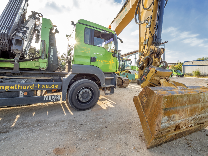 Ein Lastwagen und ein Ausleger eines Baggers auf einer Baustelle Ein Lastwagen und ein Ausleger eines Baggers auf einer Baustelle