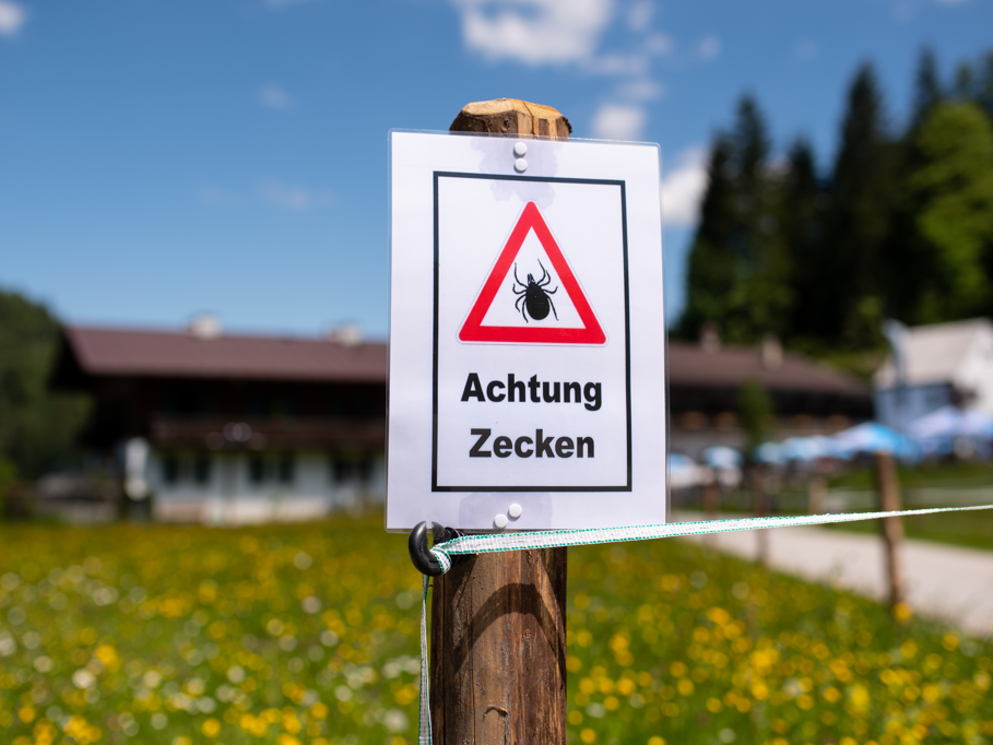 Zecken übertragen Krankheiten Ein Schild warnt an einem Wanderweg vor Zecken.