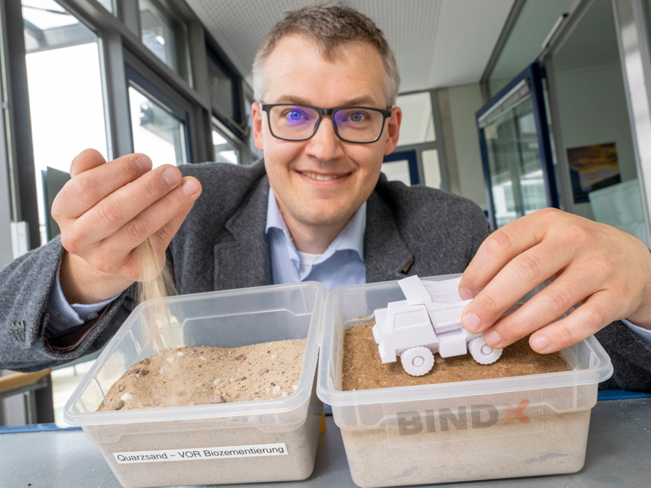 Luitpold Fried vom Start-Up-Unternehmen „Bind-X“ Luitpold Fried vom Start-Up-Unternehmen „Bind-X“ zeigt an einem Beispiel, wie mit einem speziellen Bindemittel aus ungefestigtem Sand, eine feste Verbindung entstehen kann, die zur Reduzierung von staubigen Straßen führt.