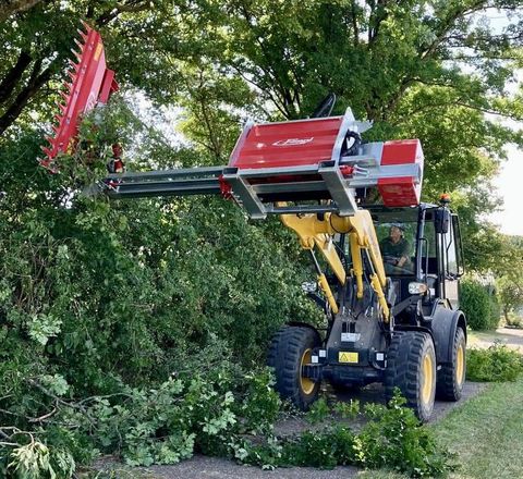 Der Radlader Komatsu WA80M-8 im Einsatz Der Radlader Komatsu WA80M-8 im Einsatz, in dem er mit seinem Anbaugeräte eine Hecke schneidet