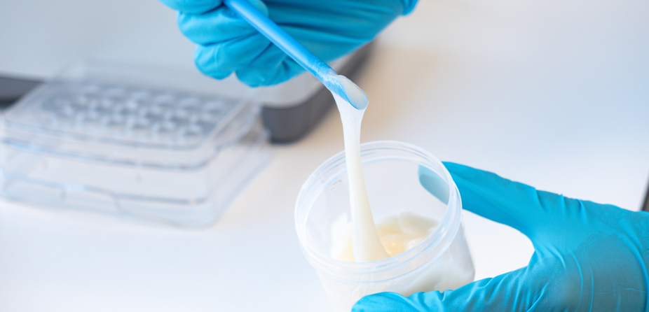 Lebender Faserverbundwerkstoff als Basis für biologisch abbaubare Materialien Hand mit blauem Laborhandschuh hält einen Becher mit der natürlichen und essbaren Emulsion aus Mycelfasern