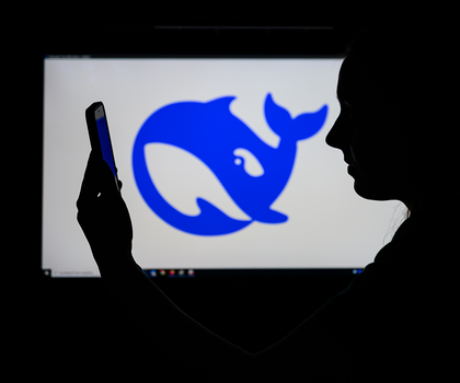 Das Logo des chinesischen KI-Start-ups DeepSeek auf einem Computerbildschirm zu sehen, während davor eine Frau auf ihr Smartphone schaut.