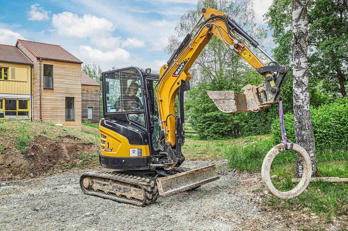 Ein Mitarbeiter bewegt mit dem Sany Minibagger ein Betonbauteil
