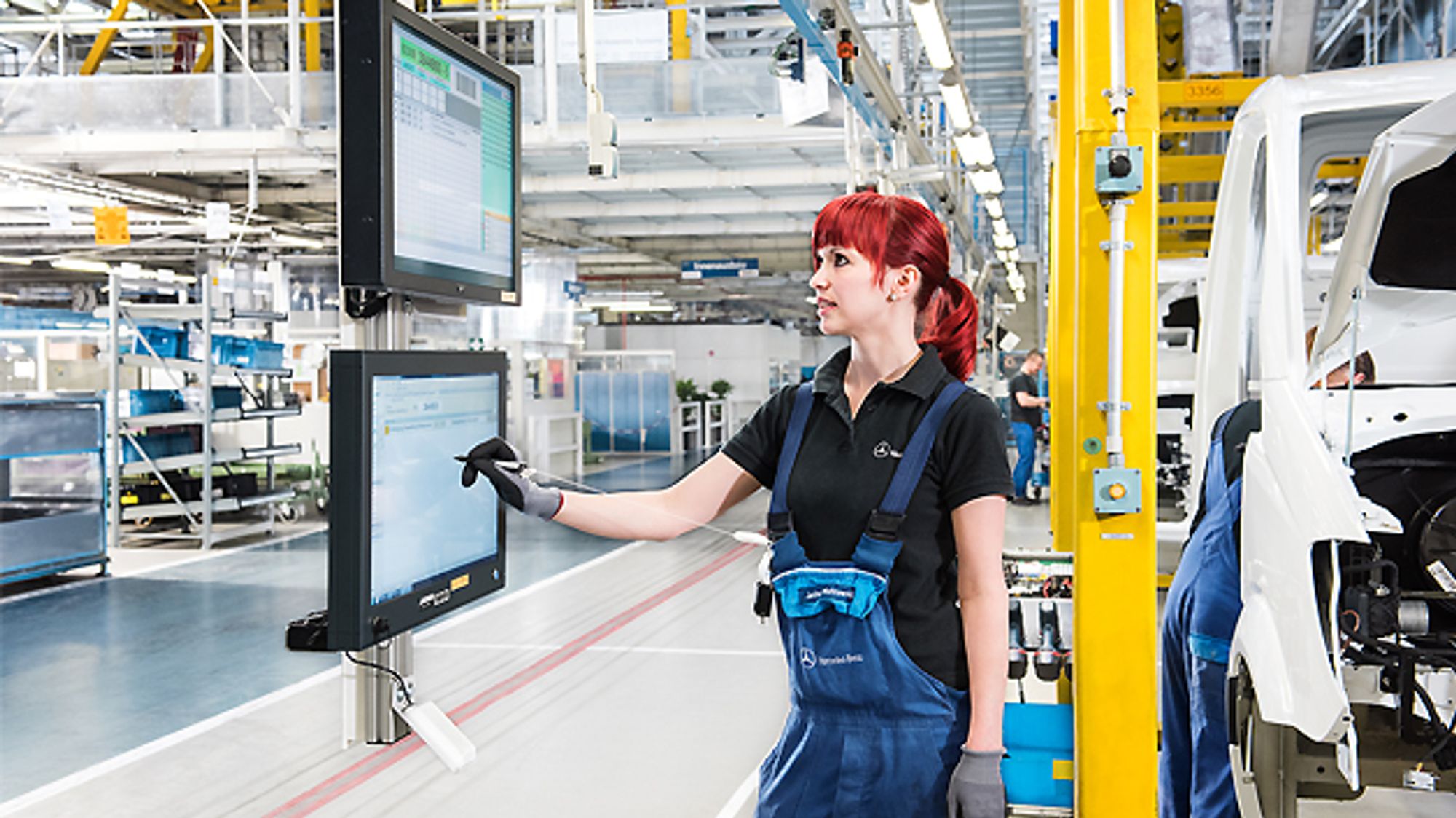 Mitarbeiterin quittiert im Mercedes-Benz-Werk Ludwigsfelde auf Touchscreens digital ihre gerade abgeschlossene Tätigkeit