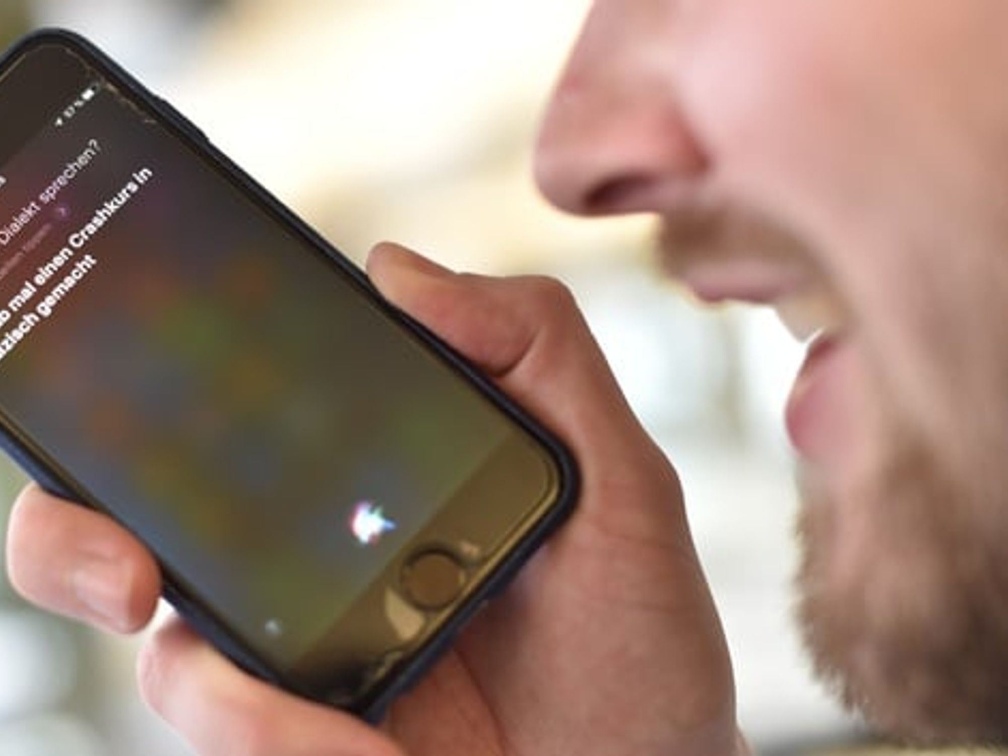 Man uses Siri voice recognition software on his smartphone Man uses Siri voice recognition software on his smartphone